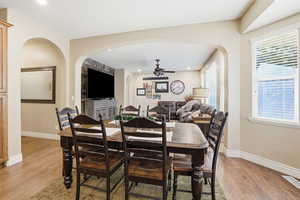 Dining room featuring arched walkways, light wood-style flooring, a ceiling fan, and recessed lighting