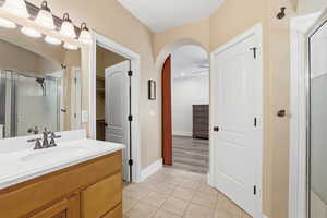 Bathroom with a shower stall, light tile patterned floors, and vanity