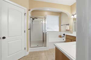 Full bathroom featuring vanity, light tile patterned flooring, a bath, and a shower stall