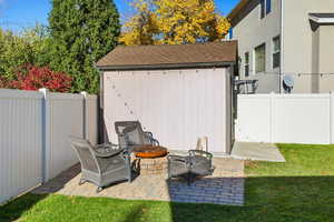 Fenced backyard featuring a patio area, a storage unit, and a fire pit