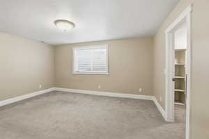 Unfurnished room featuring a textured ceiling and light colored carpet