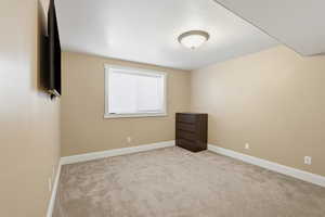 Empty room with light carpet and a textured ceiling