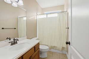 Bathroom featuring light tile patterned floors, vanity, and shower / bathtub combination with curtain
