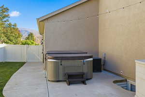 View of patio with a gate, a hot tub, and a mountain view
