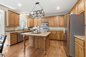 Kitchen featuring appliances with stainless steel finishes, light stone countertops, light wood-type flooring, and recessed lighting