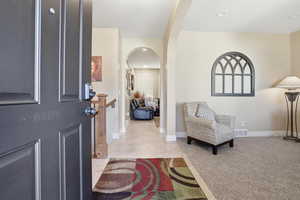 Entryway featuring arched walkways, light tile patterned flooring, recessed lighting, and light carpet
