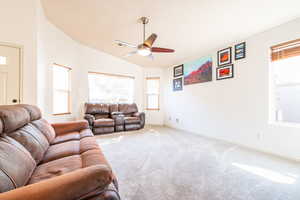 Living area with vaulted ceiling, healthy amount of natural light, carpet floors, and a ceiling fan