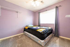 Bedroom with carpet floors, ceiling fan, and a textured wall