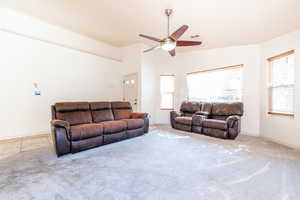Carpeted living room with healthy amount of natural light, a ceiling fan, and high vaulted ceiling