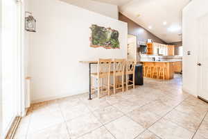 Kitchen with light countertops, lofted ceiling, open shelves, light tile patterned floors, and backsplash