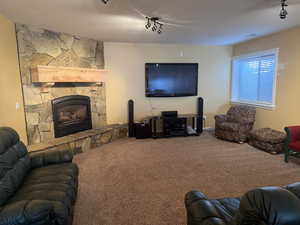 Carpeted living room with a stone fireplace and rail lighting