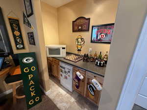 Bar area featuring white appliances, brown cabinetry, and light tile patterned floors