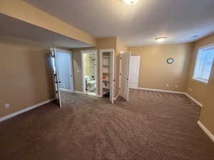 Below grade area featuring baseboards and dark carpet