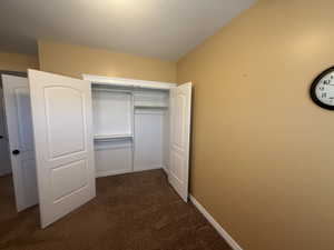 Unfurnished bedroom with dark carpet and a closet