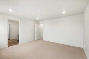 Unfurnished bedroom featuring light colored carpet, recessed lighting, and ensuite bath