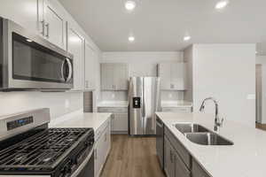 Kitchen featuring stainless steel appliances, gray cabinets, light wood-style flooring, recessed lighting, and light stone countertops