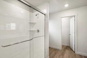 Bathroom with light wood-type flooring, a stall shower, and recessed lighting