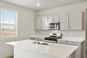 Kitchen with stainless steel appliances, an island with sink, light stone countertops, wood finished floors, and recessed lighting
