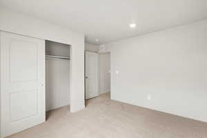 Unfurnished bedroom with light colored carpet, a closet, and recessed lighting