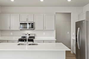 Kitchen featuring appliances with stainless steel finishes, light stone counters, light wood finished floors, recessed lighting, and white cabinetry