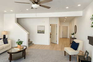 Living room with recessed lighting, stairs, a textured ceiling, ceiling fan, and light wood-style floors
