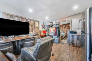 Living room with wood finished floors, a textured ceiling, lofted ceiling, and wood walls