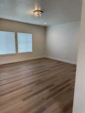 Empty room featuring a textured ceiling and light wood-type flooring