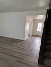 Unfurnished living room featuring dark wood finished floors, stairs, a textured ceiling, and recessed lighting