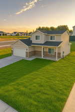 View of front of home featuring a front yard, board and batten siding, driveway, covered porch, and a shingled roof