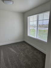 Unfurnished room with dark colored carpet and a textured ceiling