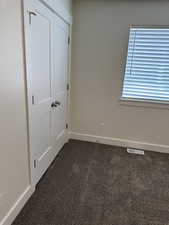 Unfurnished bedroom featuring dark colored carpet and a closet