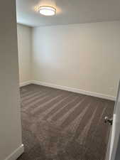 Spare room with dark colored carpet and a textured ceiling