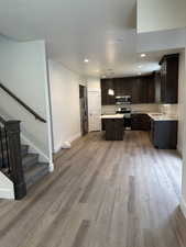 Kitchen featuring dark brown cabinets, appliances with stainless steel finishes, pendant lighting, recessed lighting, and a center island