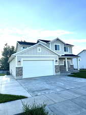 Craftsman-style home featuring driveway, a porch, a garage, board and batten siding, and brick siding
