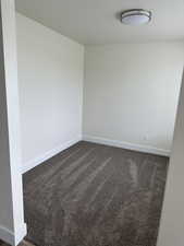 Unfurnished room with dark carpet and a textured ceiling
