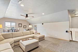 Carpeted living room featuring vaulted ceiling, a textured ceiling, recessed lighting, and a ceiling fan