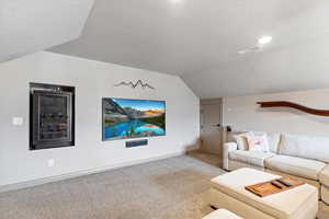 Carpeted living room with a textured ceiling and lofted ceiling