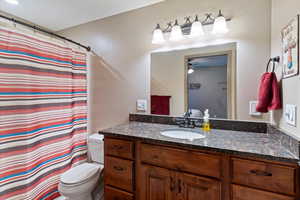 Full bathroom featuring a shower with shower curtain, vanity, and ceiling fan