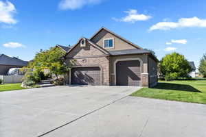 View of front of house with a front lawn, stucco siding, driveway, and brick siding