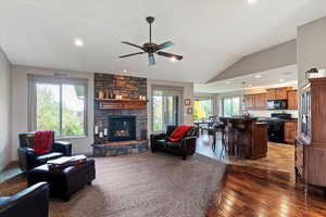Living room featuring lofted ceiling, a fireplace, recessed lighting, dark wood finished floors, and a ceiling fan