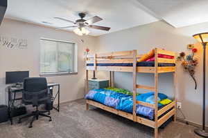 Carpeted bedroom with a ceiling fan