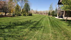 View of grassy yard featuring a balcony