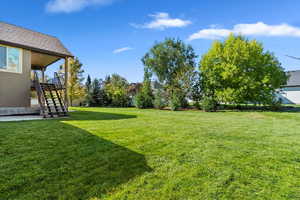 View of grassy yard with stairs and a patio area