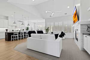 Living room featuring a glass covered fireplace, recessed lighting, healthy amount of natural light, vaulted ceiling, and a ceiling fan