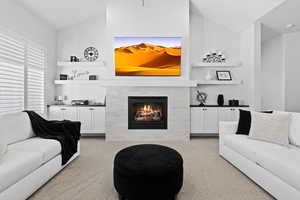 Living room with light carpet, a fireplace, vaulted ceiling, and built in features