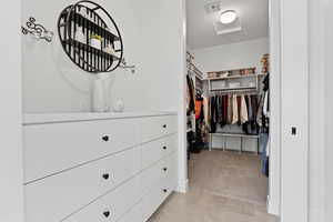 Walk in closet featuring light carpet, light tile patterned flooring, and attic access