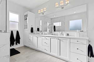 Full bath with a marble finish shower and double vanity