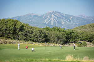 View of community featuring view of golf course, a mountain view, and a yard