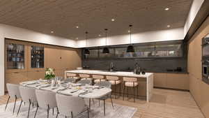 Kitchen featuring glass insert cabinets, a kitchen bar, hanging light fixtures, wood ceiling, and a kitchen island with sink