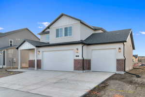 View of front of home with brick siding, driveway, and roof with shingles